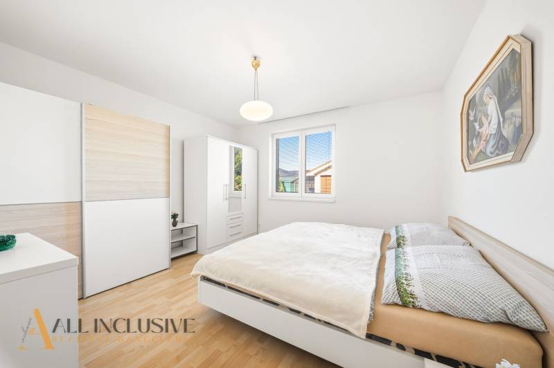 Na predaj 4-izb. rodinný dom s garážou, Kútniky - Spálňa v rodinnom dome s podlahou s dreveným dekorom, bielym nábytkom a obrazom.