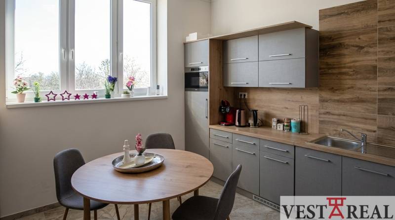 Prenájom klimatizovaná kancelária: 25 m2 a 42 m2 - Trnava Chovateľská - Kuchynský kút v kanceláriách s oknom, dreveným dekorom a jedálenským stolom.