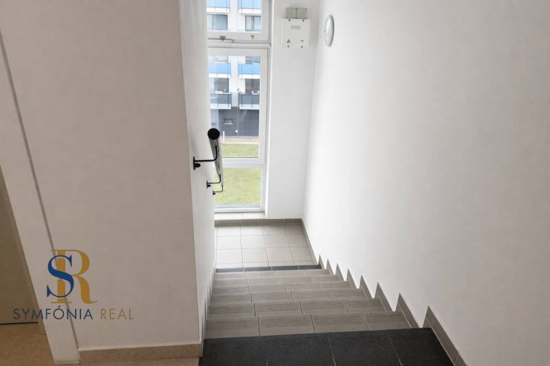 NOVOSTAVBA (2019) + PARKOVANIE | 2-izbový byt 69 m² – Bratislava - Schodisko vo vnútri bytového domu s výhľadom von cez okno.