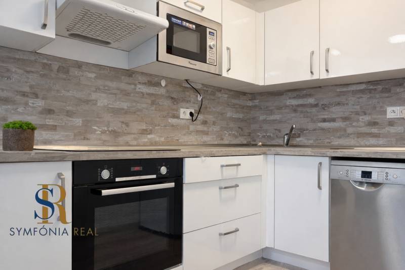 NOVOSTAVBA (2019) + PARKOVANIE | 2-izbový byt 69 m² – Bratislava - Kuchyňa v 2-izbovom byte s bielymi skrinkami a vstavanými spotrebičmi.