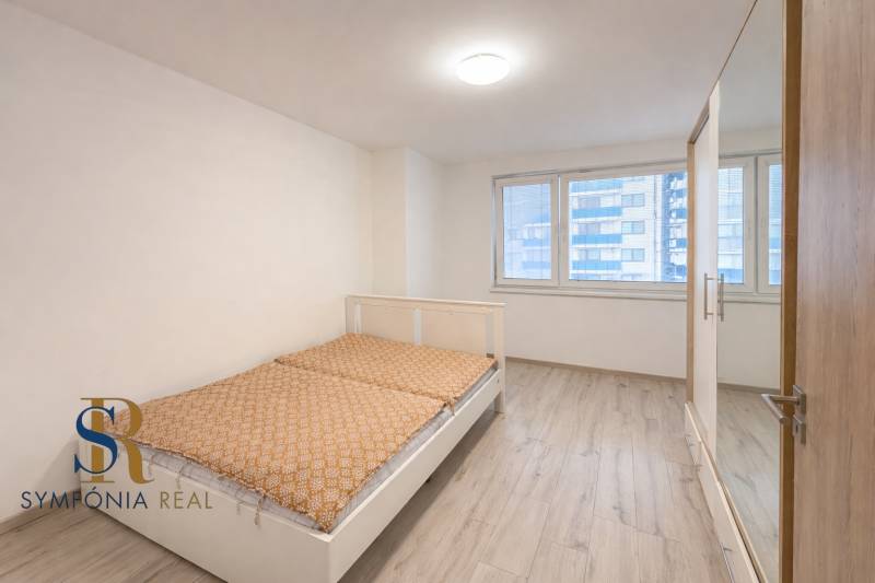 NOVOSTAVBA (2019) + PARKOVANIE | 2-izbový byt 69 m² – Bratislava - Spálňa s posteľou a šatníkovou skriňou, podlaha s dreveným dekorom v 2-izbovom byte.