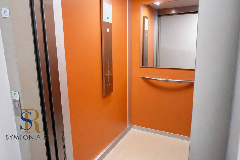 NOVOSTAVBA (2019) + PARKOVANIE | 2-izbový byt 69 m² – Bratislava - Interiér oranžového výťahu so zrkadlom a ovládacím panelom.