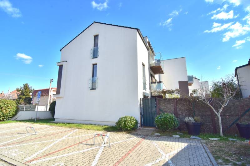 UHLISKÁ, 3-i byt, 80 m2 – zariadená novostavba s parkovaním v cene - Budova so sklenenými balkónmi a parkovací priestor na ulici Uhliská v Bratislave, Vajnory.