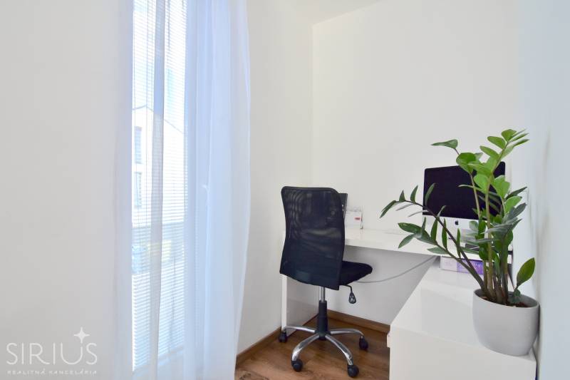 UHLISKÁ, 3-i byt, 80 m2 – zariadená novostavba s parkovaním v cene - Pracovný kút s počítačom, čiernou stoličkou a rastlinou na podlahe s dreveným dekorom.