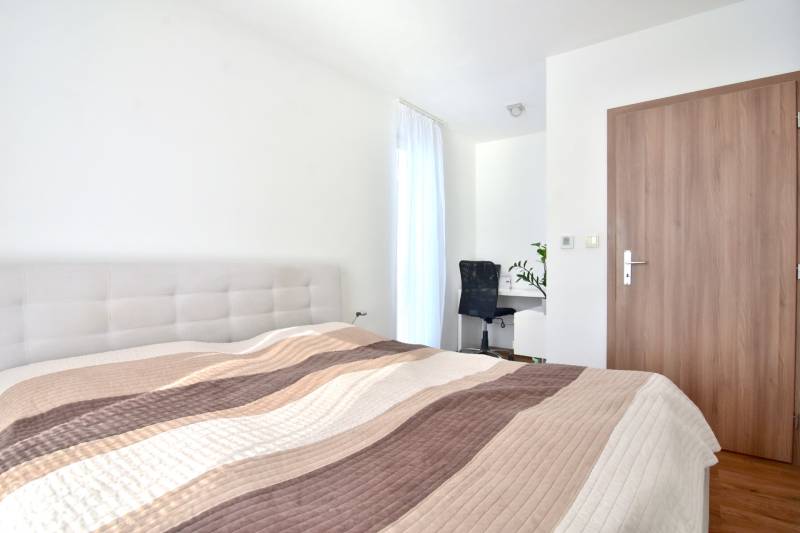 UHLISKÁ, 3-i byt, 80 m2 – zariadená novostavba s parkovaním v cene - Svetlá spálňa s posteľou, pracovným stolom a podlahou s dreveným dekorom v 3-izbovom byte.