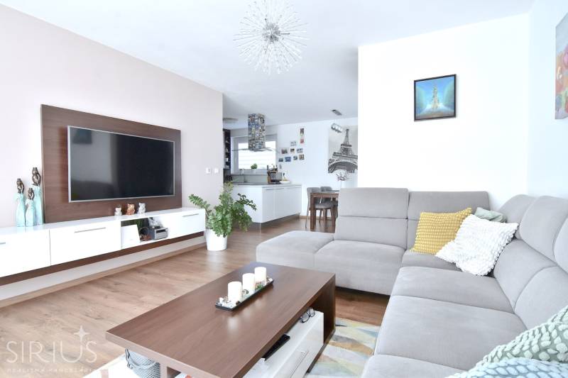 UHLISKÁ, 3-i byt, 80 m2 – zariadená novostavba s parkovaním v cene - Obývacia izba v 3-izbovom byte s podlahou s dreveným dekorom a sivou sedačkou.