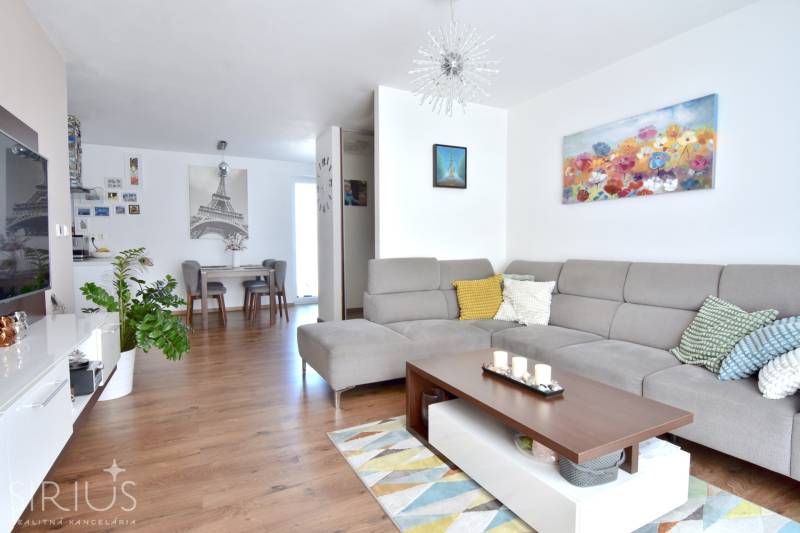 UHLISKÁ, 3-i byt, 80 m2 – zariadená novostavba s parkovaním v cene - Obývacia izba v 3-izbovom byte s pohovkou, dekoráciami a podlahou s dreveným dekorom.