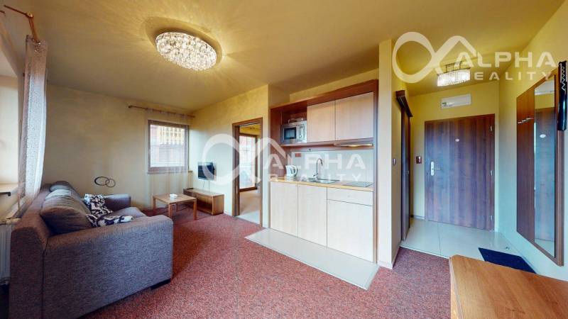 PRENÁJOM 2i apartmán s terasou, parkovaním, Veľká Lomnica - Obývacia izba v 2-izbovom byte so sedačkou a kuchynskou linkou.