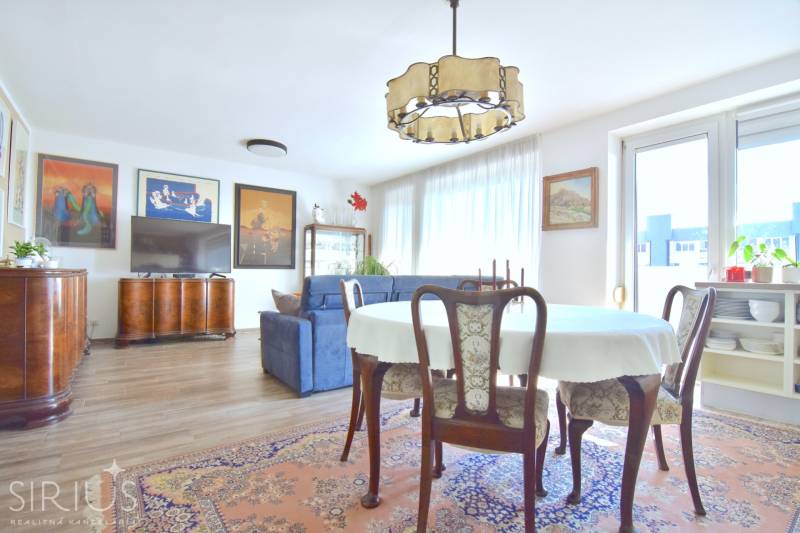 PRI VINOHRADOCH, 3-i byt s veľkými loggiami, 113 m2, RAČANY BIANCO - Obývacia izba s jedálenským stolom, pohovkou a podlahou s dreveným dekorom v 3-izbovom byte.