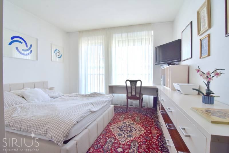 PRI VINOHRADOCH, 3-i byt s veľkými loggiami, 113 m2, RAČANY BIANCO - Svetlá spálňa s kreslom, posteľou a kobercom v 3-izbovom byte.