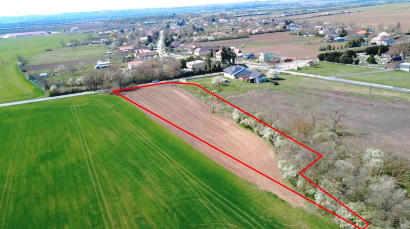 Ondrejovce – 4.665 m2 POZEMOK na rekreačnú chatu na hranici obce - Letecký pohľad na poľnohospodársku plochu v Ondrejovciach obklopenú záhradami a dedinou.