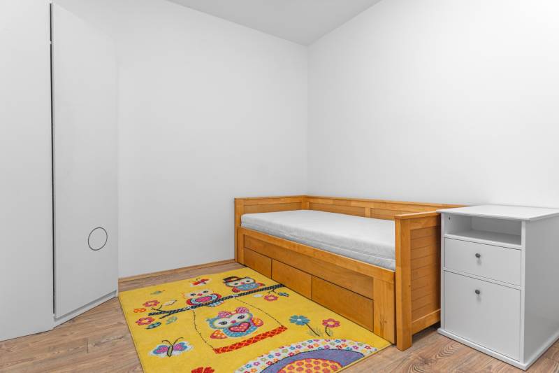 I Predaj štýlového tehlového domu v Rajke pri Bratislave - Jednolôžková posteľ s úložným priestorom, koberec so vzorom, podlaha s dreveným dekorom.