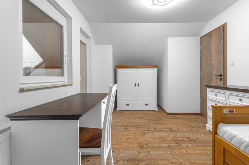 I Predaj štýlového tehlového domu v Rajke pri Bratislave - Izba v rodinnom dome s podlahou s dreveným dekorom, stolom a bielym nábytkom.