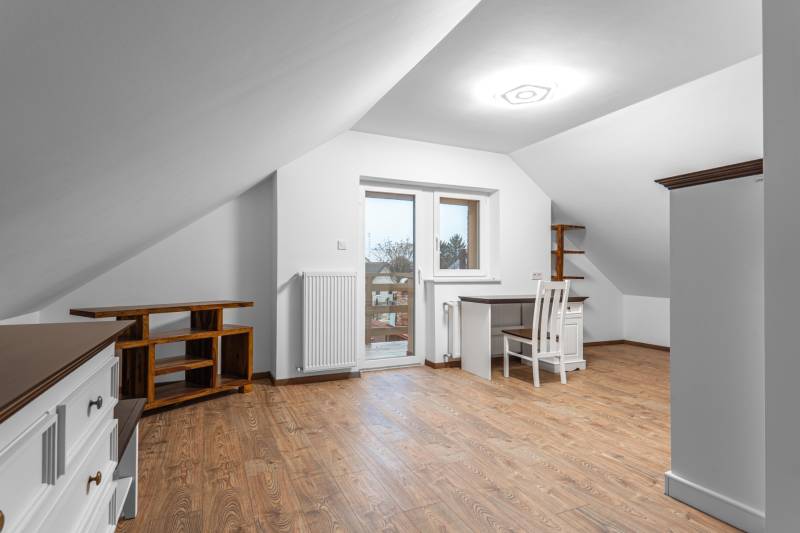 I Predaj štýlového tehlového domu v Rajke pri Bratislave - Podkrovná miestnosť v rodinnom dome s pracovným stolom a podlahou s dreveným dekorom.
