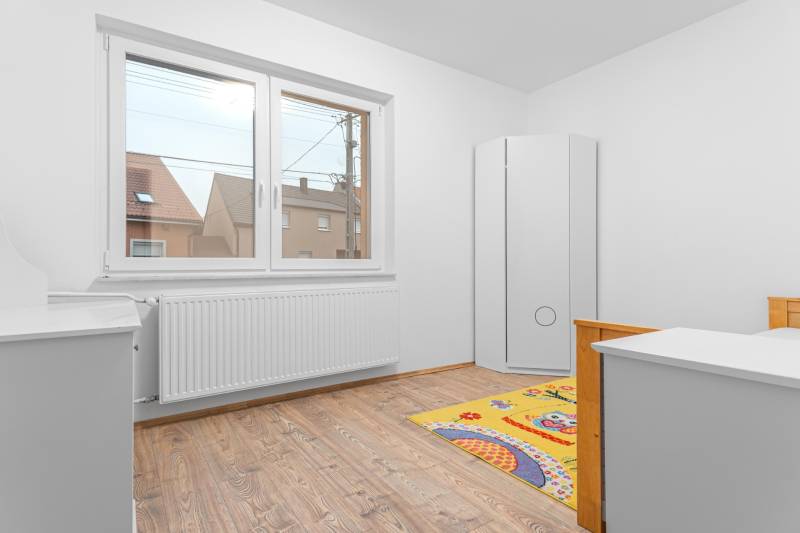 I Predaj štýlového tehlového domu v Rajke pri Bratislave - Detská izba s bielym nábytkom a podlahou s dreveným dekorom v rodinnom dome.