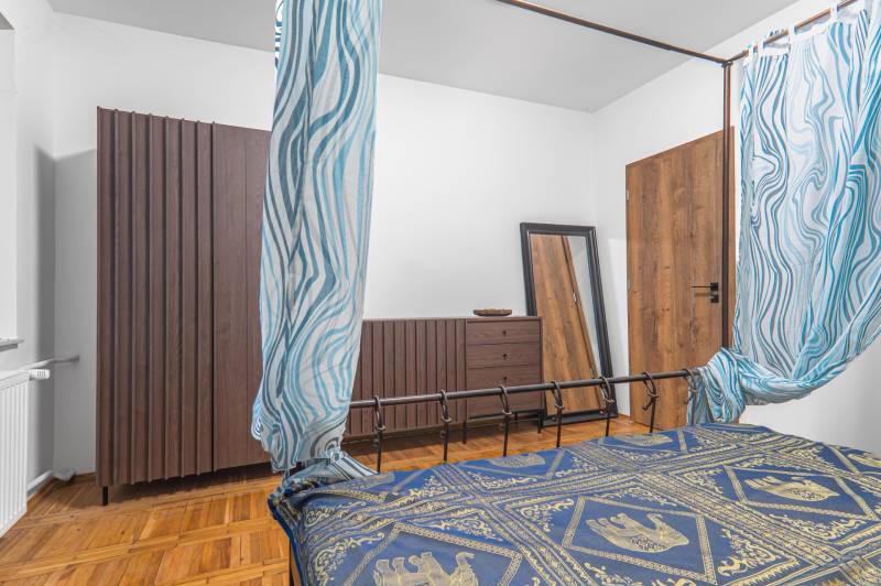 I Predaj štýlového tehlového domu v Rajke pri Bratislave - Spálňa v rodinnom dome s podlahou s dreveným dekorom, vzorované závesy a zrkadlo.