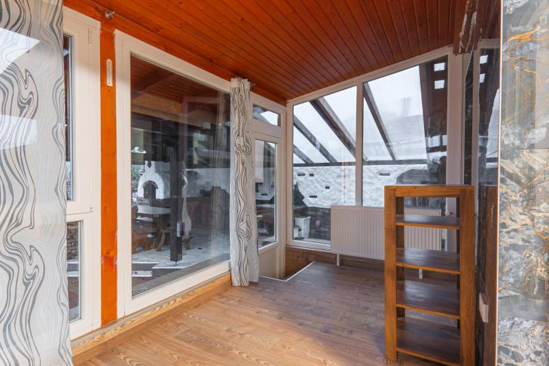 I Predaj štýlového tehlového domu v Rajke pri Bratislave - Interiér rodinného domu s presklenou stenou, závesmi a podlahou s dreveným dekorom.