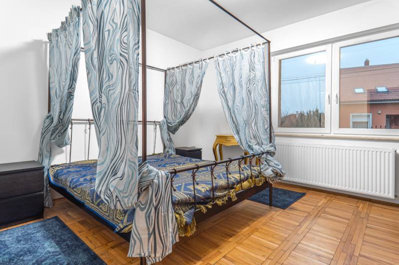 I Predaj štýlového tehlového domu v Rajke pri Bratislave - Spálňa s posteľou s baldachýnom, podlaha s dreveným dekorom a veľkým oknom.