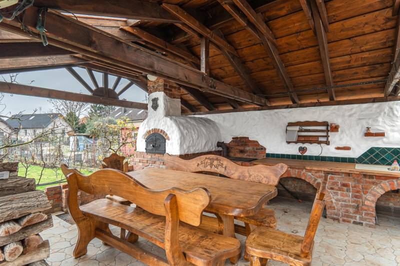 I Predaj štýlového tehlového domu v Rajke pri Bratislave - Drevený altánok s pecou a dreveným nábytkom pri rodinnom dome v Rajke na Jókai Mór ulici.