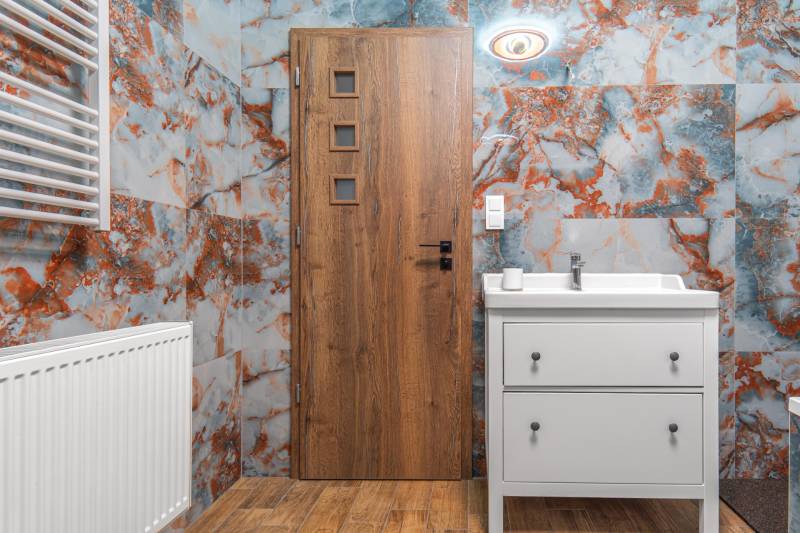 I Predaj štýlového tehlového domu v Rajke pri Bratislave - Kúpeľňa v rodinnom dome s farebnými stenami, drevenými dverami a umývadlom.