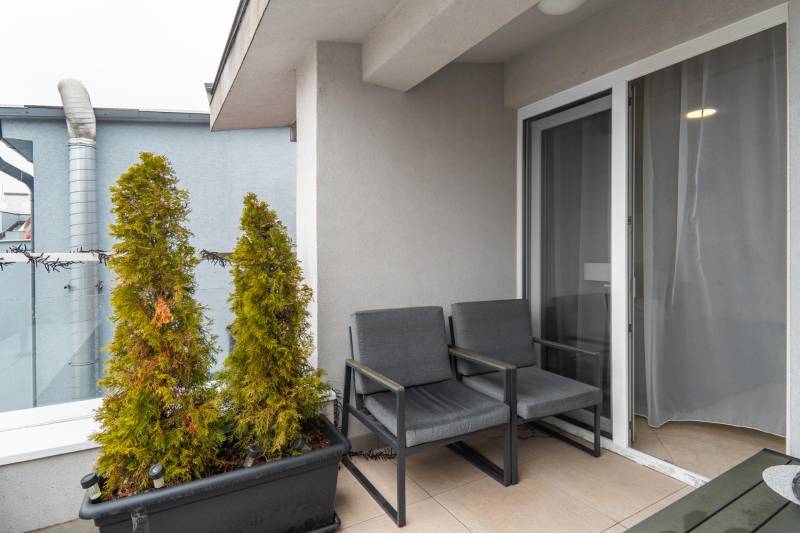 I Exkluzívny penthouse s terasou v absolútnom centre mesta - Balkón s dvoma kreslami, kvetináčmi a zaťahovacími dverami v 2-izbovom byte.