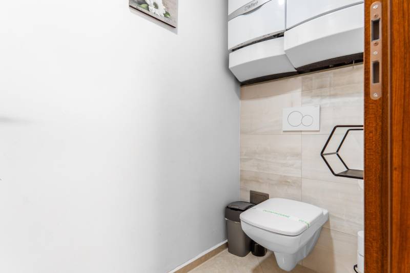 I Exkluzívny penthouse s terasou v absolútnom centre mesta - Toaleta s nástenným WC v 2-izbovom byte a šedým odpadkovým košom.