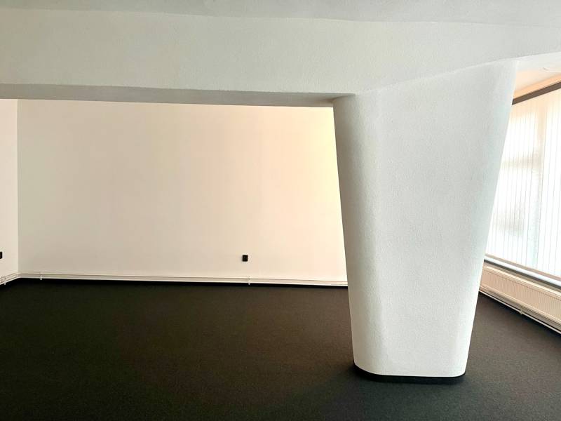 I Kompletne zrekonštruovaný nebytový priestor v Novom Meste - Prázdna kancelária s béžovými stenami, čiernou podlahou a veľkým oknom.