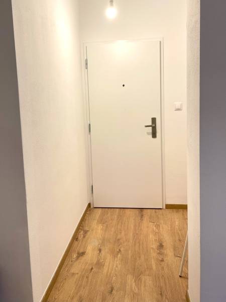 I Predaj 3i bytu v novostavbe v Rači - V dolnej časti fotografie je chodba 3-izbového bytu s podlahou s dreveným dekorom.