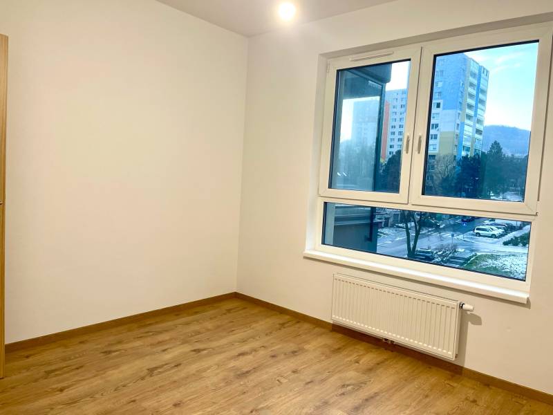 I Predaj 3i bytu v novostavbe v Rači - Izba v 3-izbovom byte s veľkým oknom a podlahou s dreveným dekorom.