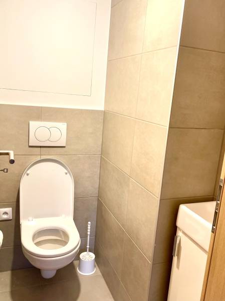 I Predaj 3i bytu v novostavbe v Rači - Kúpeľňa v 3-izbovom byte s WC, obkladmi a toaletnou kefou v rohu.