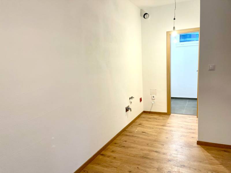 I Predaj 3i bytu v novostavbe v Rači - Prázdna miestnosť s podlahou s dreveným dekorom v 3-izbovom byte.