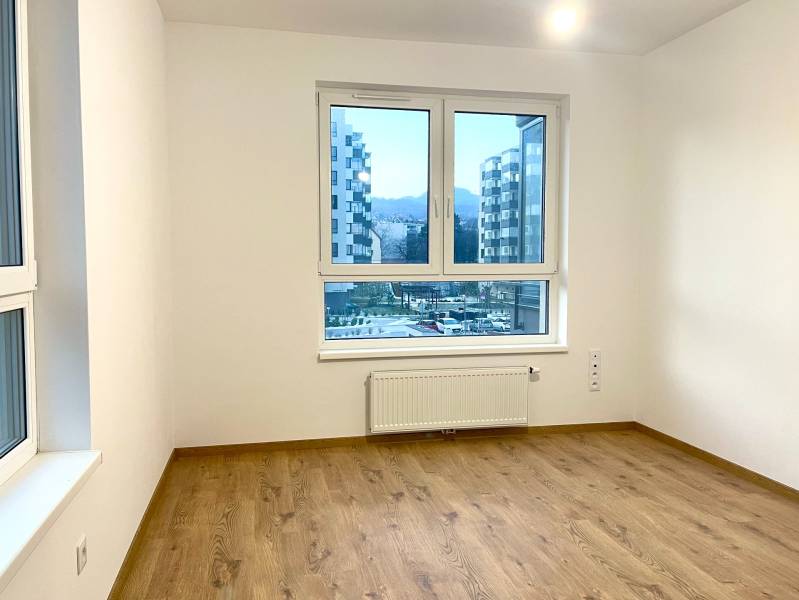 I Predaj 3i bytu v novostavbe v Rači - Izba s bielymi stenami a podlahou s dreveným dekorom v 3-izbovom byte.