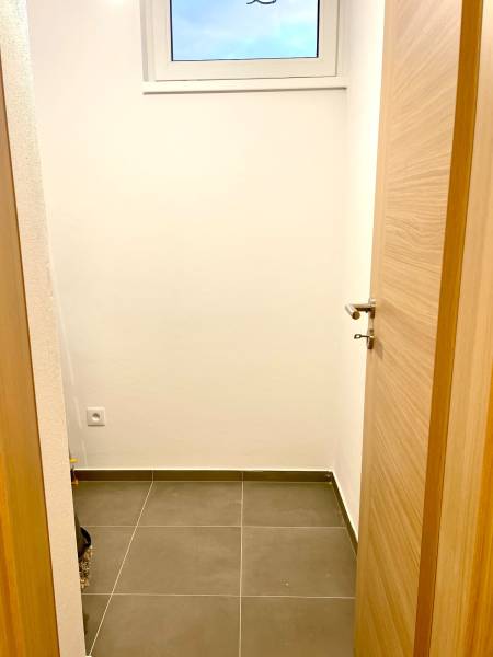 I Predaj 3i bytu v novostavbe v Rači - Malá miestnosť so svetlou stenou, svetlý dverný rám, okno a dlažba.