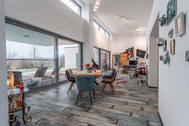 I PREDAJ moderná vila s bazénom a veľkým pozemkom - Interiér Vily s podlahou s dreveným dekorom, jedálenským stolom a posedením pre hostí.