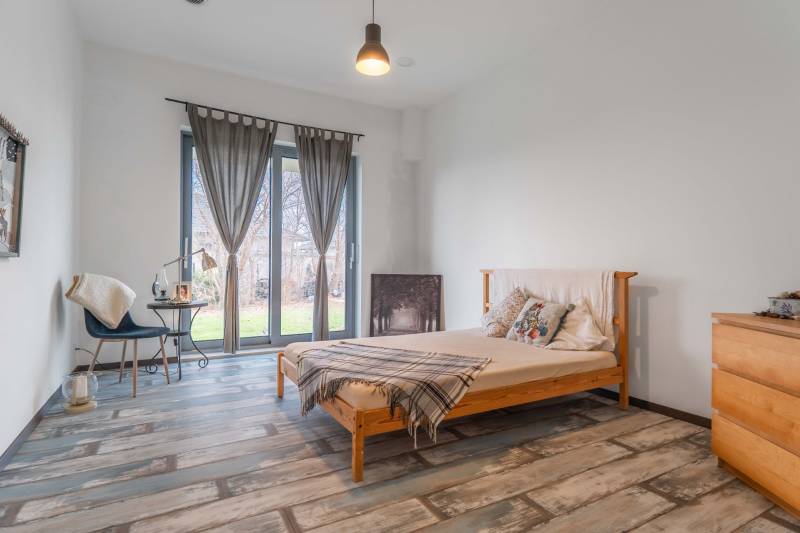 I PREDAJ moderná vila s bazénom a veľkým pozemkom - Spálňa vo vile s posteľou, písacím stolom, závesmi a podlahou s dreveným dekorom.