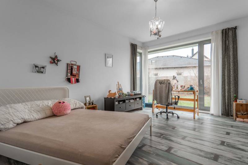 I PREDAJ moderná vila s bazénom a veľkým pozemkom - Spálňa vo Vile s posteľou, stolom, stoličkou a podlahou s dreveným dekorom.