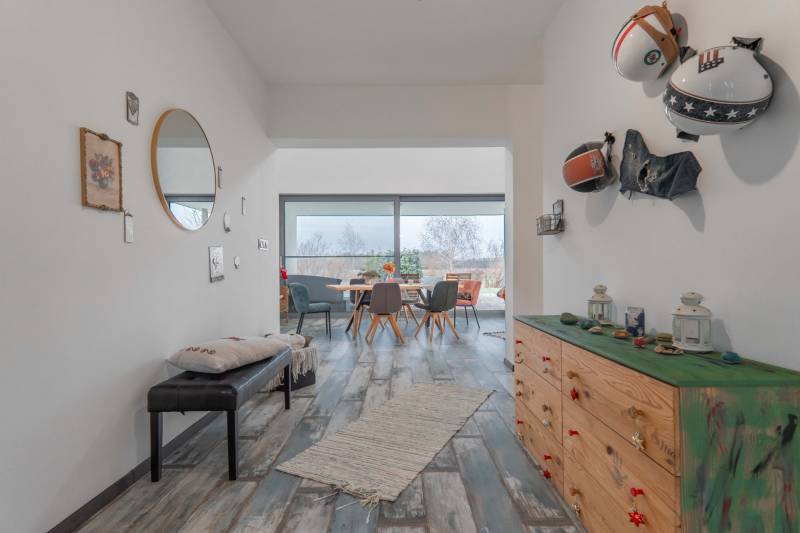 I PREDAJ moderná vila s bazénom a veľkým pozemkom - Chodba vo vile s dekorovanými stenami, podlaha s dreveným dekorom, zrkadlo, nábytok a výhľad.