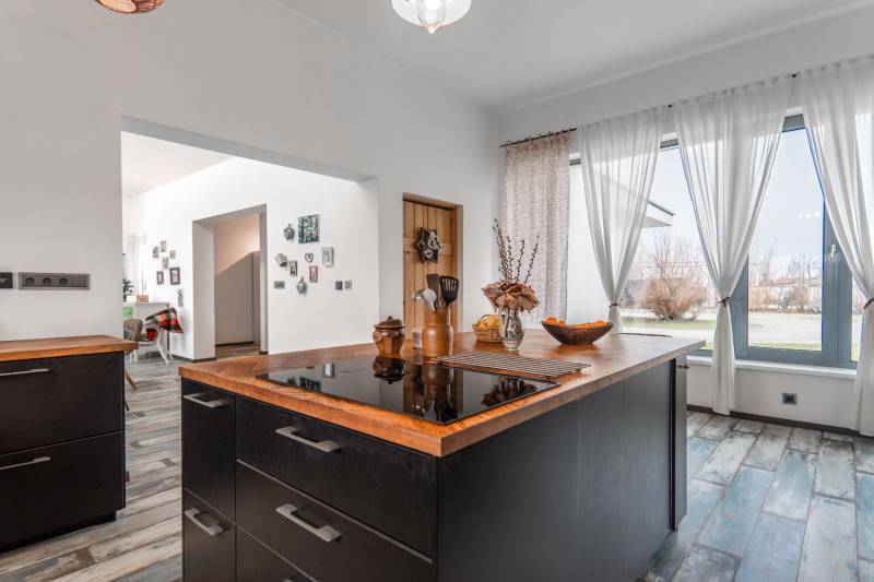 I PREDAJ moderná vila s bazénom a veľkým pozemkom - Moderná kuchyňa vo vile s podlahou s dreveným dekorom, závesmi a dekoráciami.