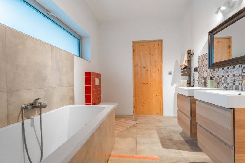 I PREDAJ moderná vila s bazénom a veľkým pozemkom - Kúpeľňa vo vile s podlahou s dreveným dekorom, vaňou a farebnými obkladmi.