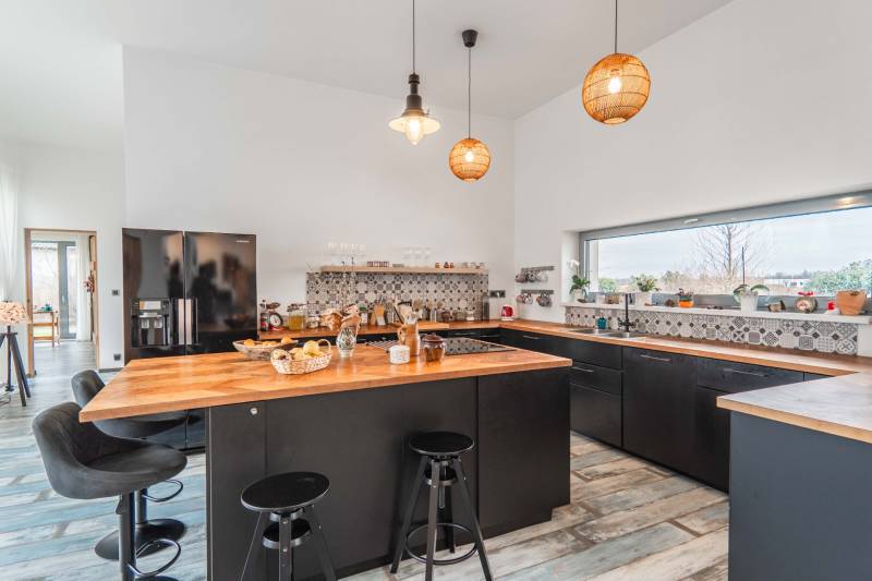 I PREDAJ moderná vila s bazénom a veľkým pozemkom - Kuchyňa v rodinnom dome s čiernym nábytkom, dreveným dekorom a veľkým oknom.