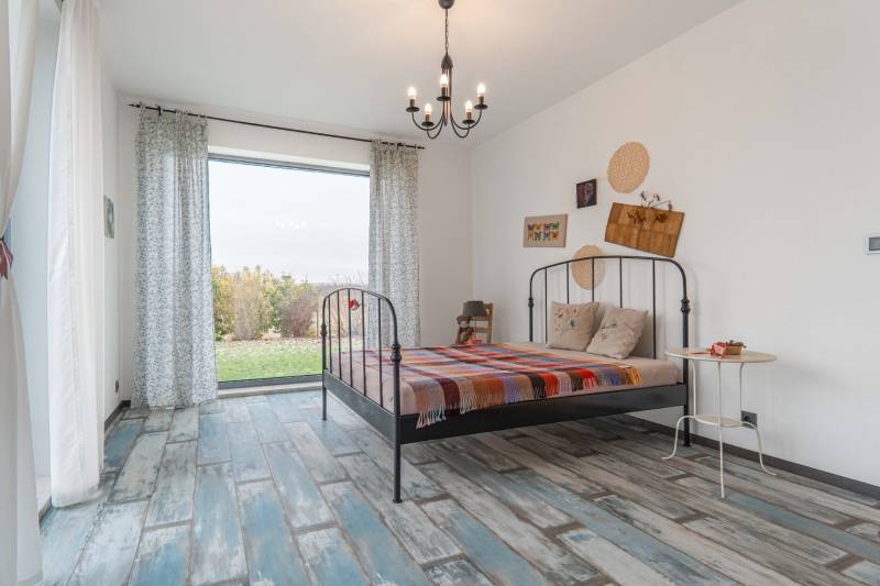 I PREDAJ moderná vila s bazénom a veľkým pozemkom - Minimalistická spálňa vo vile s kovovou posteľou, farebným prehozom a dekoráciami.