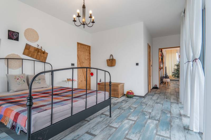 I PREDAJ moderná vila s bazénom a veľkým pozemkom - Spálňa vo vile so vzorovanou prikrývkou, lustrom a dekoratívnymi predmetmi na stene.