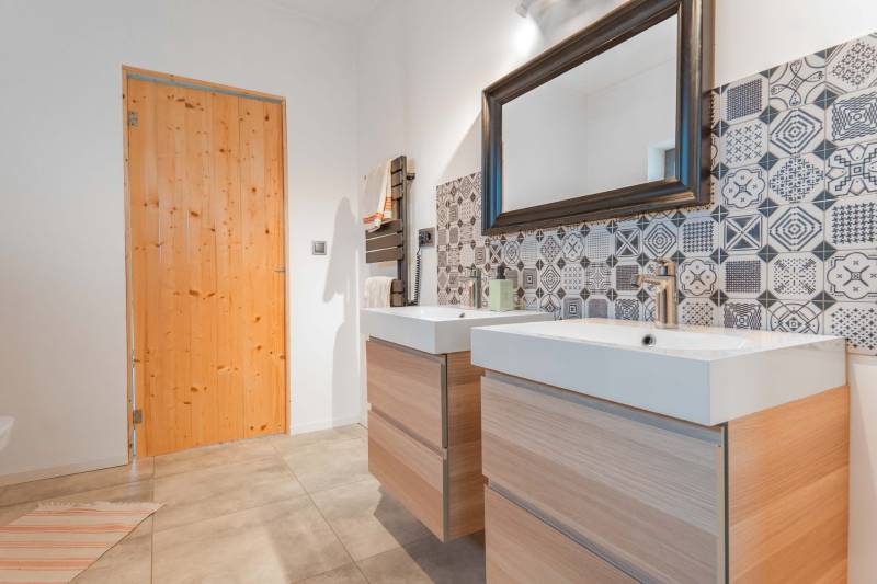I PREDAJ moderná vila s bazénom a veľkým pozemkom - Kúpeľňa vo Vile so vzorovanými obkladačkami, dvojumývadlom a drevenými dverami.