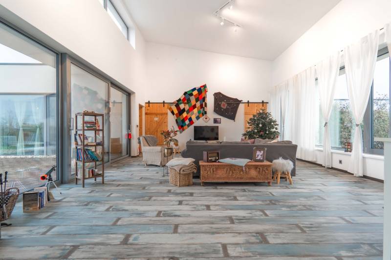 I PREDAJ moderná vila s bazénom a veľkým pozemkom - Obývačka vo vile s podlahou s dreveným dekorom, pohovkou a knižnicou.