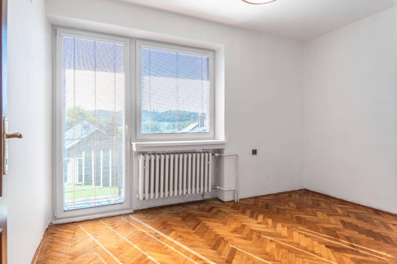 I Na predaj dvojposchodový 5i rodinný dom pri Žiline - Izba v rodinnom dome s podlahou s dreveným dekorom a veľkým oknom.