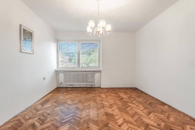 I Na predaj dvojposchodový 5i rodinný dom pri Žiline - Prázdna izba v rodinnom dome s podlahou s dreveným dekorom a lustrom.