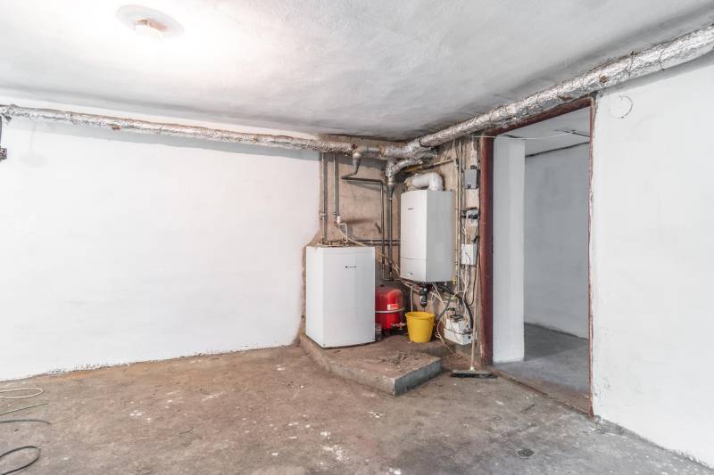 I Na predaj dvojposchodový 5i rodinný dom pri Žiline - Technická miestnosť v rodinnom dome s kotlom a potrubiami na betonovej podlahe.