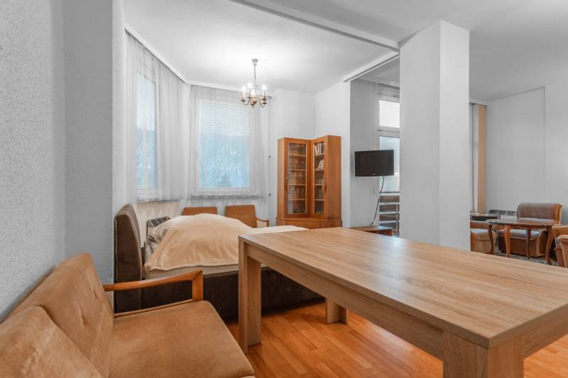 I Predaj bytu v Semmeringu, Rakúsko – výborná investícia - Obývacia časť 1-izbového bytu s pohovkami, stolom a podlahou s dreveným dekorom.
