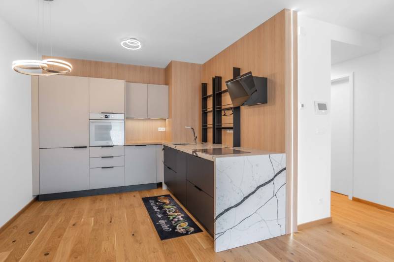 : Nadštandardný 2-i byt v projekte ZWIRN za cenu „štandardu“ - Kuchyňa v 2-izbovom byte s drevenou podlahou a modernými spotrebičmi.