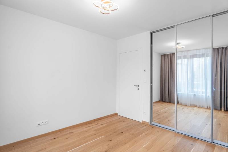 : Nadštandardný 2-i byt v projekte ZWIRN za cenu „štandardu“ - Prázdna miestnosť so vstavanou skriňou, drevenou podlahou a veľkým oknom v 2-izbovom byte.